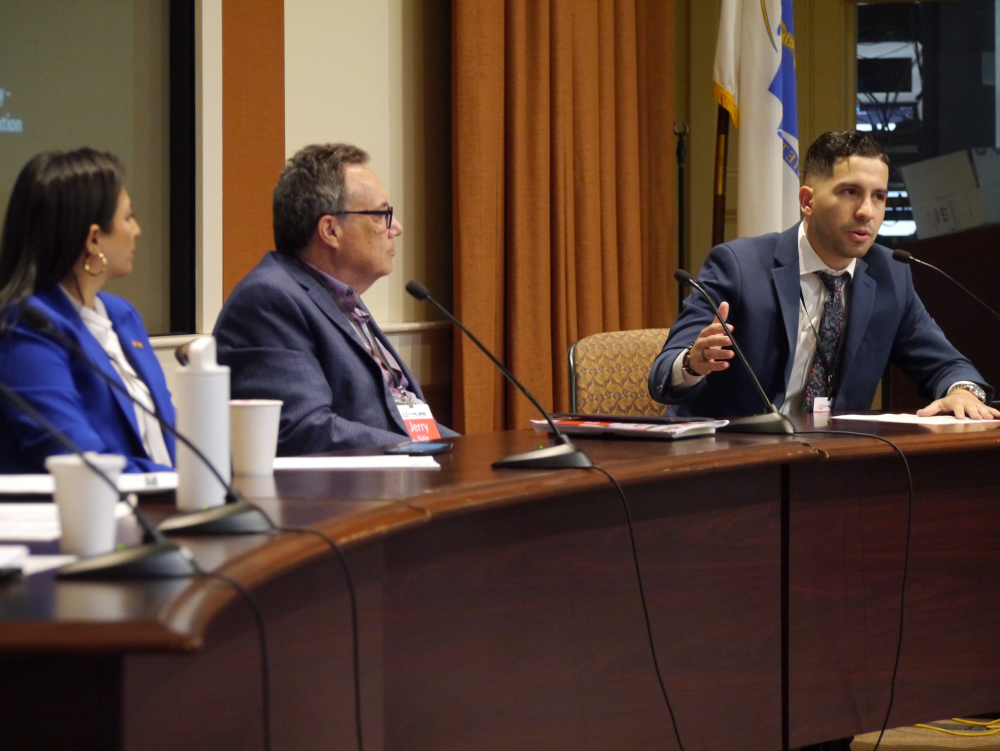 State Representative Andy Vargas, seated at a table, addresses a gathering to discuss the Latino community and the state economy.