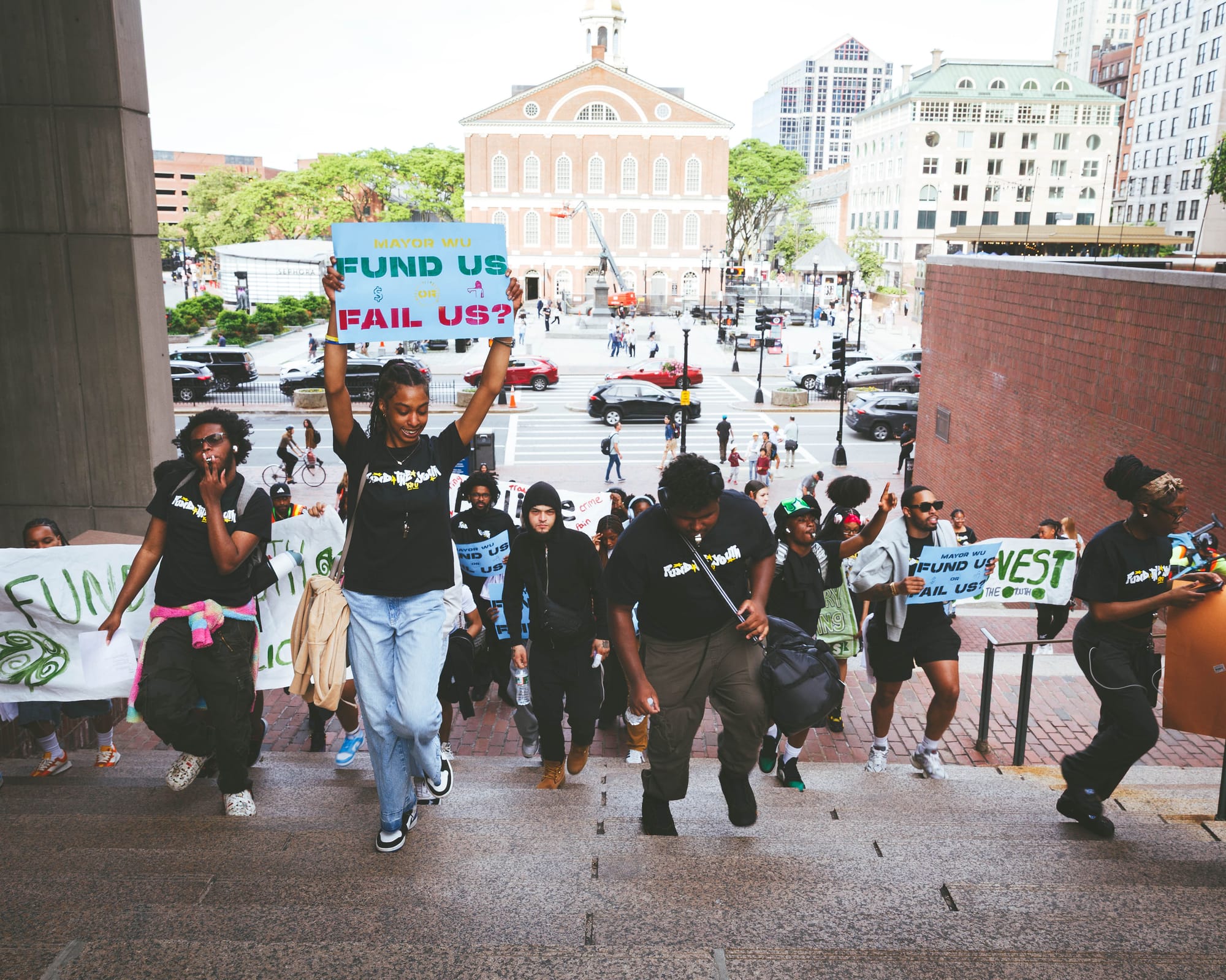 Teens with the group Youth Justice Power Union march on City Hall, holding signs calling for more funding for youth services