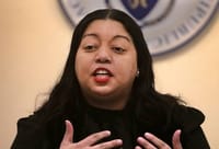 Senator Liz Miranda speaks at a podium in a State House hearing room.