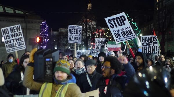 Protestors holding signs with anti-war slogans march near Park Street Station.
