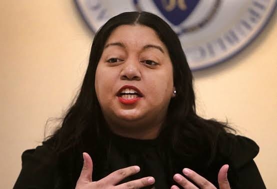 Senator Liz Miranda speaks at a podium in a State House hearing room.